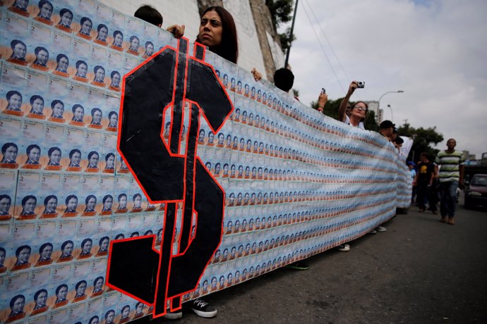 Demonstrators hold a banner made from three thousand two-bolivar-bills, that is 