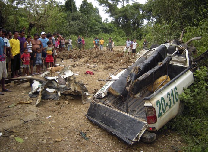 Residents look at the remains of a police car, damaged after a landmine explosio