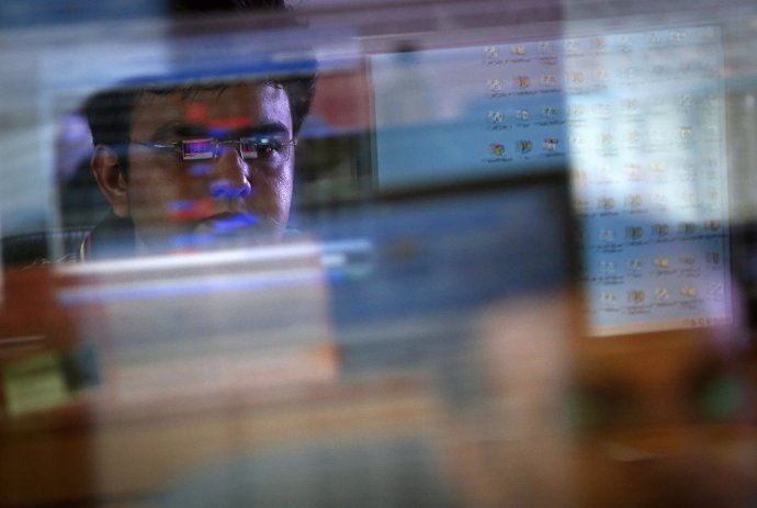 A broker monitors share prices while trading at a brokerage firm in Mumbai Augus