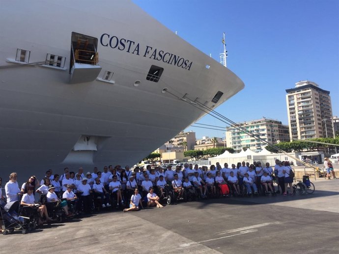 Socios y familiares de Aspaym posan junto al barco en el que harán el crucero