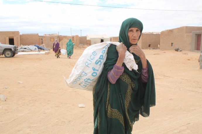 Una refugiada saharaui carga un saco con comida 
