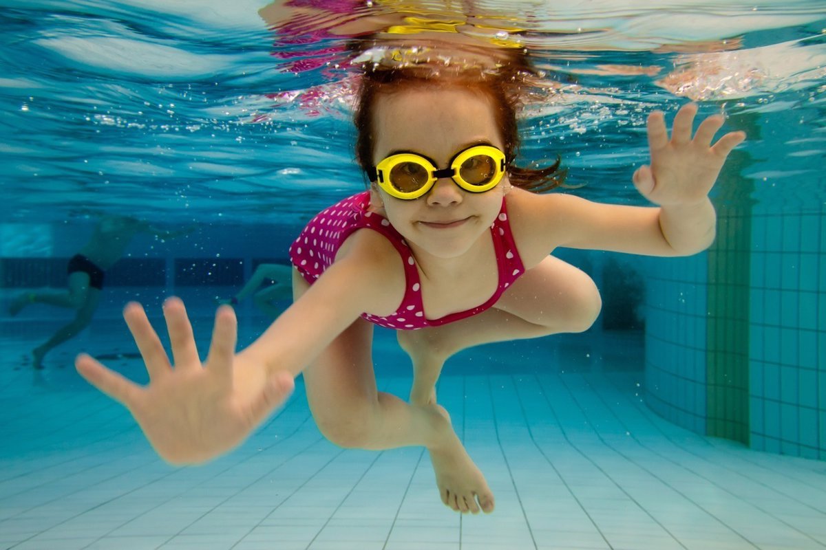 Una mujer con gafas de natación está bajo el agua.
