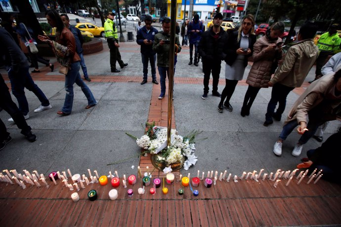 People stand next to candles lit for victims after an explosive device detonated