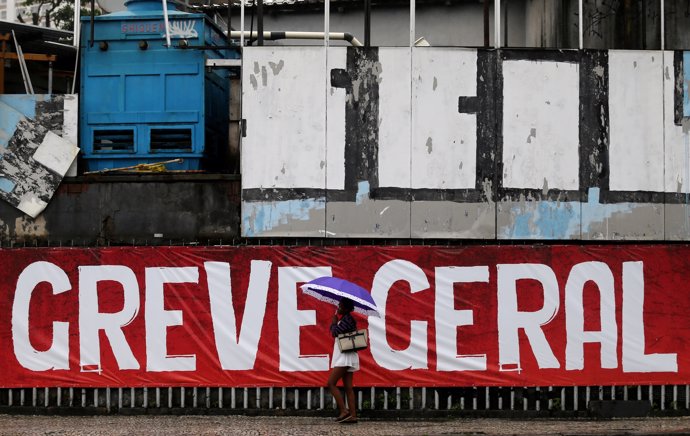 A woman walks past a sign that reads "General Strike" during a general strike ag