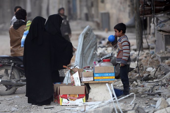 Dos mujeres compran en un puesto a un niño en Al Bab