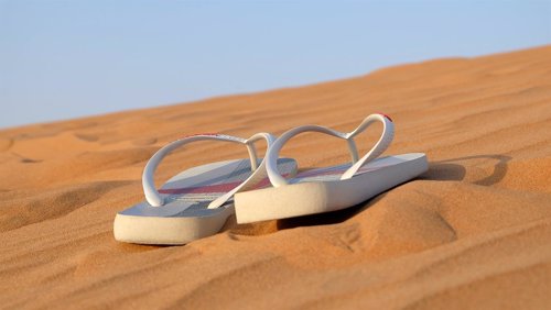 Vacaciones, sandalias en la arena de la playa
