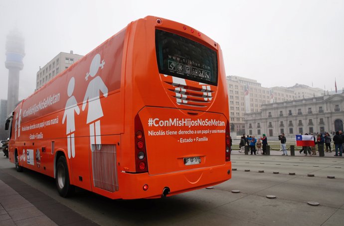 LGBT activists stand outside the presidential palace La Moneda as a bus with the