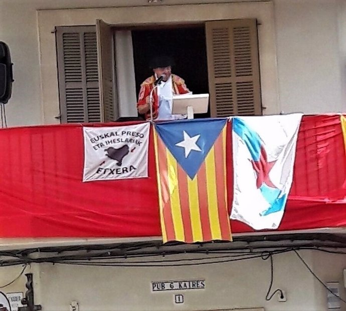 Momento del pregón de Llubí con bandera apoyo a presos de ETA