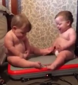Dos bebés disfrutan vibrando sobre una máquina de fitness