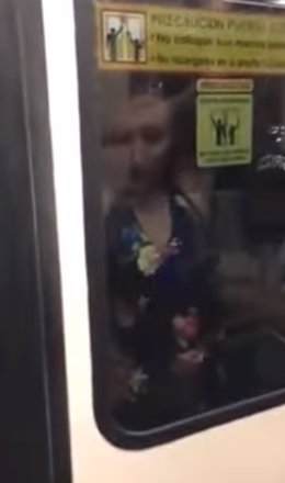 Mujer viaja colgada de la puerta del metro