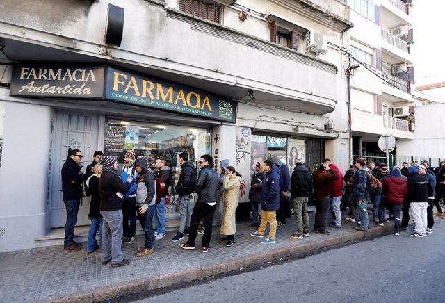 People queue in line outside of a pharmacy to buy legal marijuana in Montevideo,