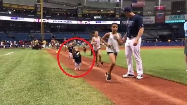 Niña baila en una carrera en un campo de baseball