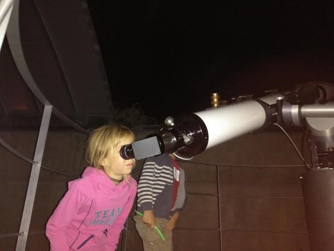 Niños mriando por un telescopio