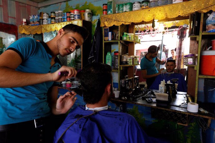 A Syrian barber gives a man a haircut at the main market in Al Zaatari 