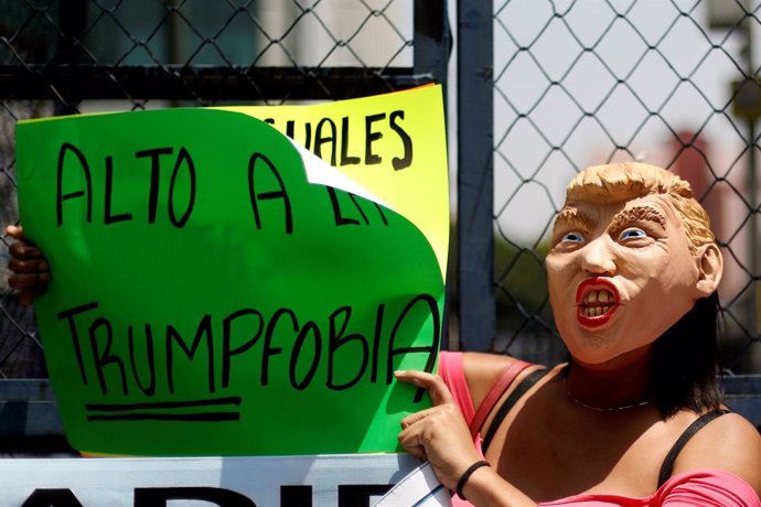 Una mujer sostiene una pancarta durante una protesta contra el veto de Trump.