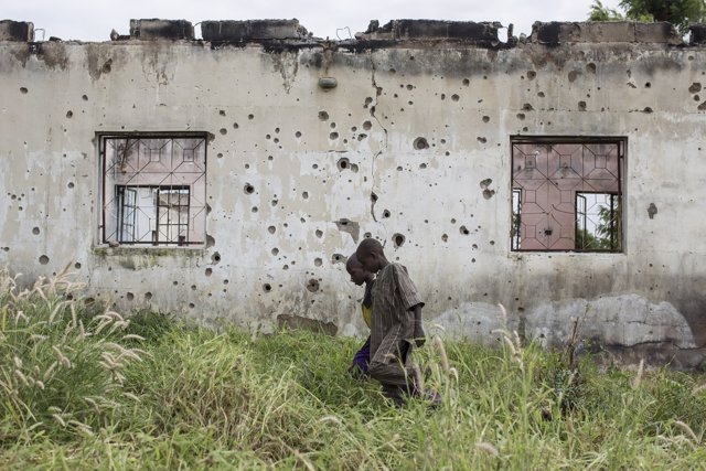 Niños pasean junto a una pared llena de agujeros de bala en Nigeria