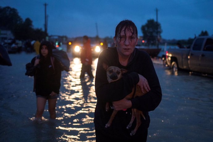 Una mujer sostiene a su perro tras evacuar su vivienda por las inundaciones. 