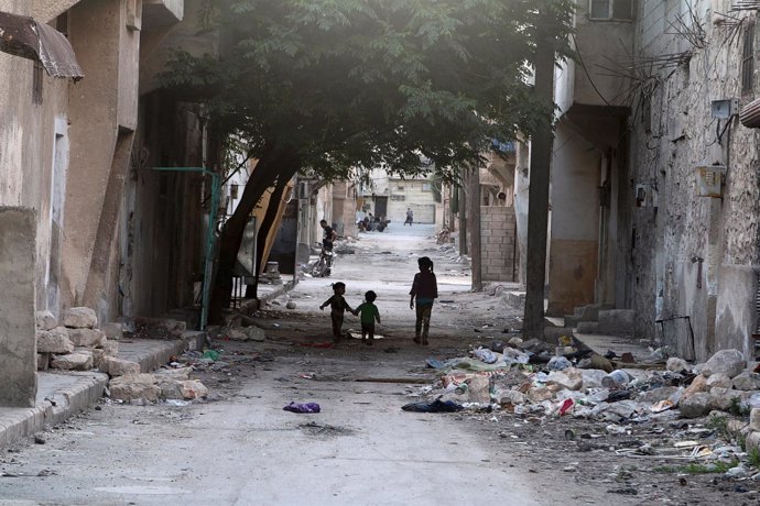 Niños caminando entre escombros en un barrio de Alepo (Siria)