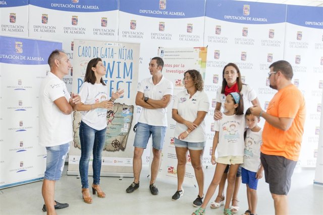 La diputada Ángeles Martínez junto a tres de los nadadores del reto solidario.