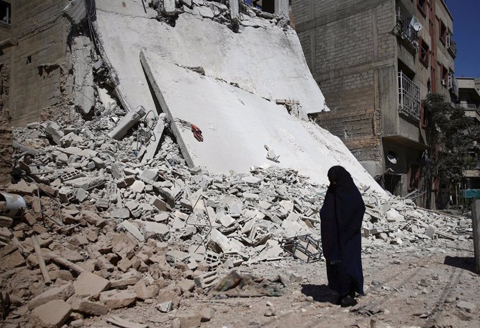 Una mujer al pie de un edificio derrumbado por un bombardeo en Damasco