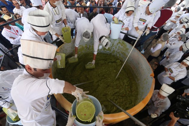 Volunteers from a culinary school mix mashed avocados as they attempt to set a n