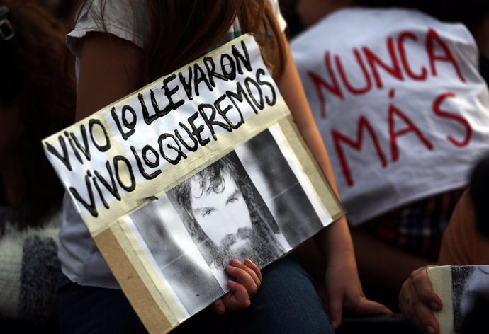 A girl holds a portrait of Santiago Maldonado, a protester who has been missing 