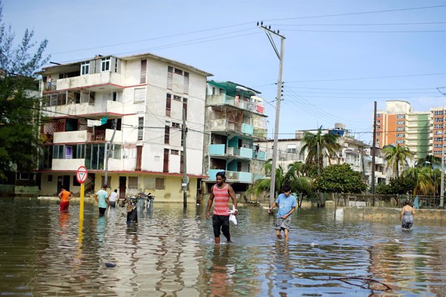 People walk in a flooded area after Hurricane Irma caused flooding and a blackou