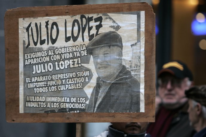 A man holds a banner with a picture of Jorge Julio Lopez, who's been missing for