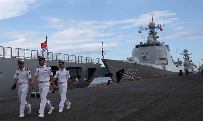 Oficiales de la marina China junto a un buque de guerra chino