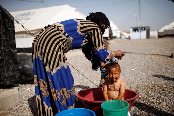 Una madre lava a su hijo en un campo para desplazados de Mosul