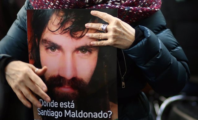 A woman holds a portrait of Santiago Maldonado, a protester who has been missing