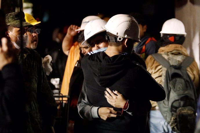 Workers hug during the search for students at Enrique Rebsamen school after an e