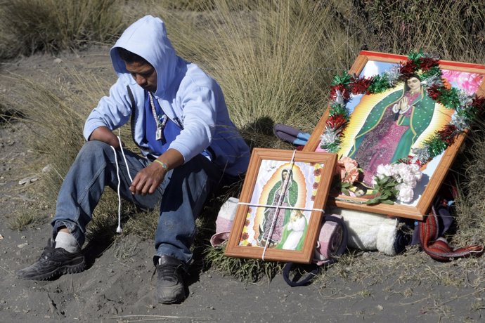 A pilgrim sits next to pictures of the Virgin of Guadalupe in Paso de Cortes, in