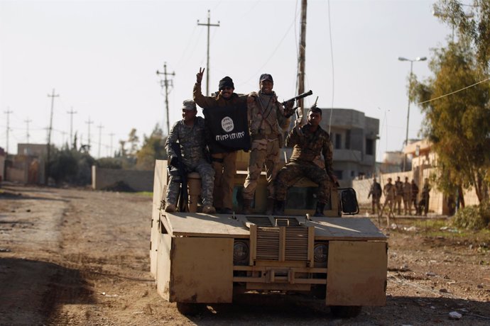 Militares iraquíes posan con la bandera de Estado Islámico en Mosul