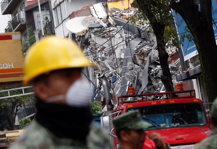 A soldier looks on next to a collapsed building after an earthquake in Mexico Ci