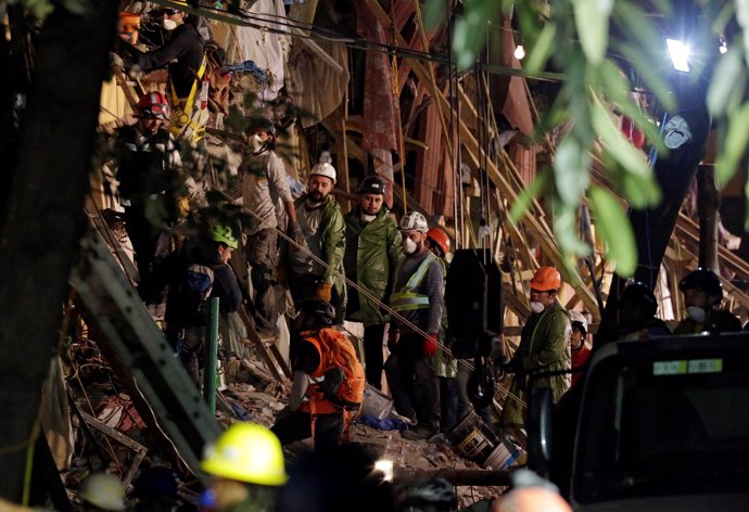 Rescue workers stand next to the rubble of a collapsed multi family residential 
