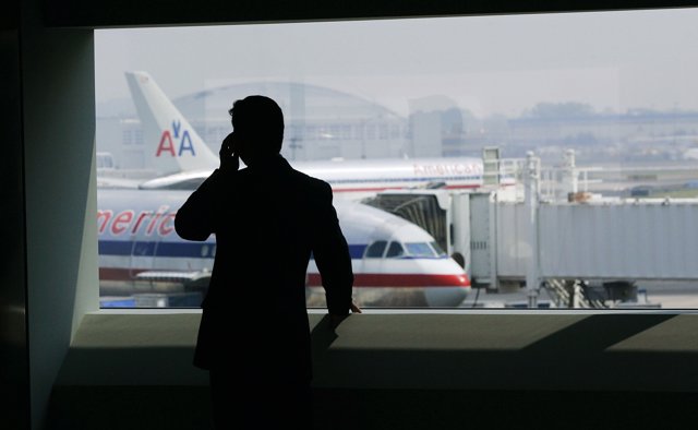 Persona hablando por teléfono en el aeropuerto con aviones de American Airlines 