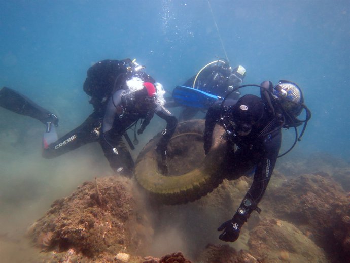 Dos buceadores limpian fondos marinos rueda residuos