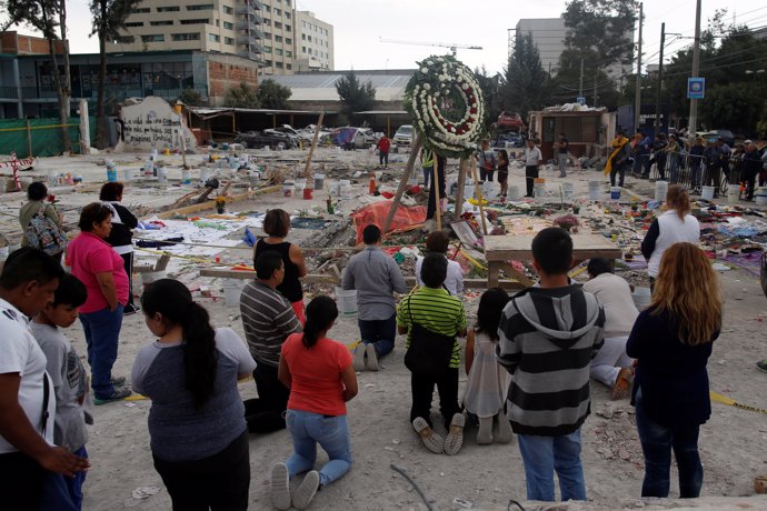 Residents pray for victims at a makeshift altar, in an area that used to be a te