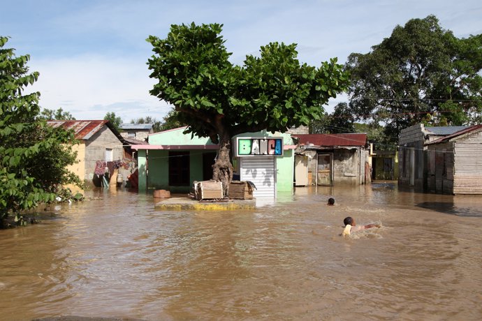 Children swim in a street flooded by the overflow of the Yuna River, in the afte