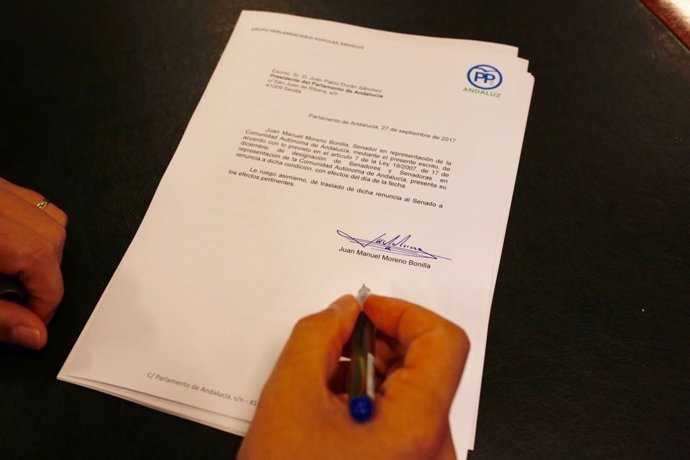 El presidente del PP-A, Juanma Moreno, firma su renuncia como senador