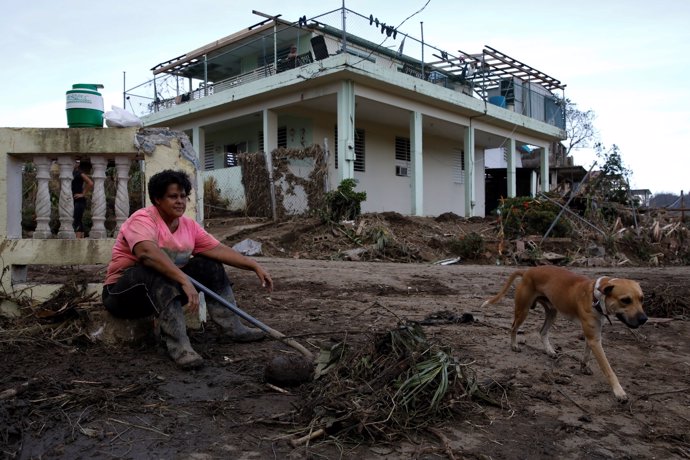 Carmen Marrero takes a rest while she cleans debris from her house after the are