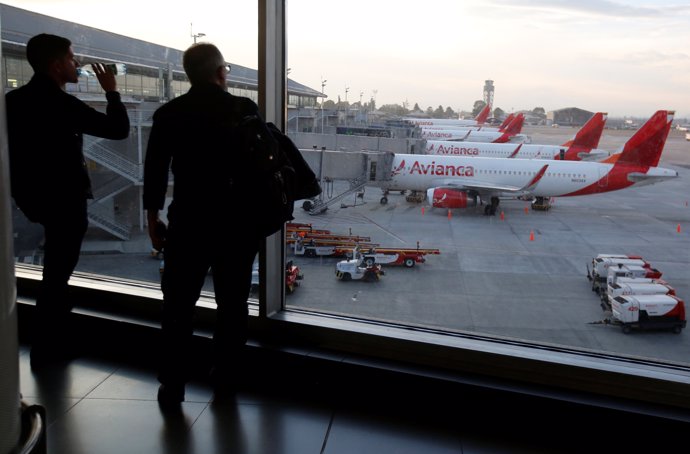 Passengers look at aircrafts of Colombian airlines Avianca as the airline's flig