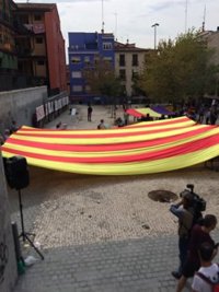 Unas 50 personas despliegan una gran señera en un plaza de Lavapiés a favor del referéndum