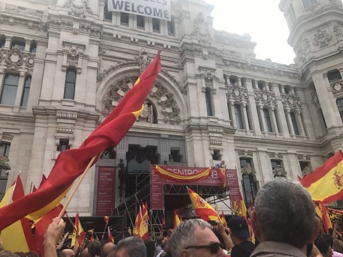 Dues persones col·loquen banderes espanyoles a la bastida de Cibeles