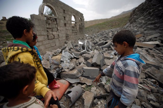 Niños junto a una casa destruida en un bombardeo en Saná