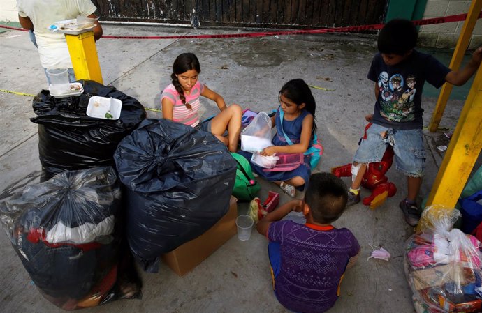 Niños sentados en el suelo tras los terremotos de México
