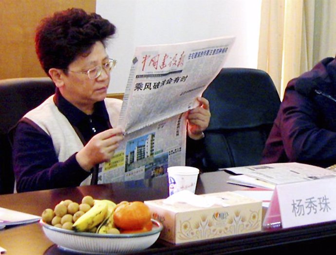 Yang Xiuzhu reads a newspaper during a meeting in Wenzhou, Zhejiang province, De