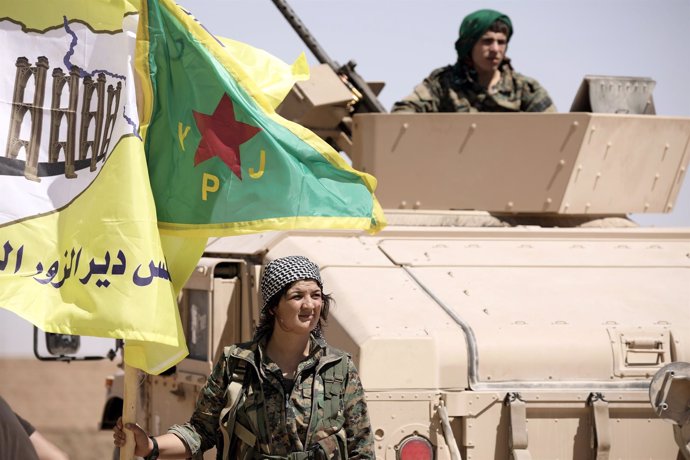 Una miliciana de las FDS junto a un carro de combate