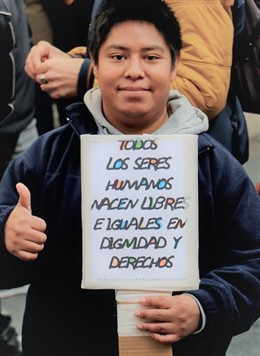 Un joven sujeta un cartel por el respeto a la dignidad y los derechos